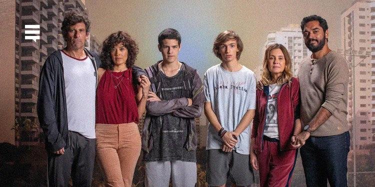 Elenco de Os Outros à frente de um banner representando a imagem de prédios condominiais