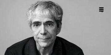 Homem branco, cabelo branco, enquadramento da foto na altura do peito. Seu semblante é sério.