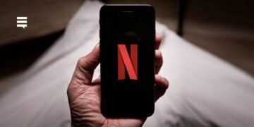 Mão segurando celular conectado no aplicativo da Netflix